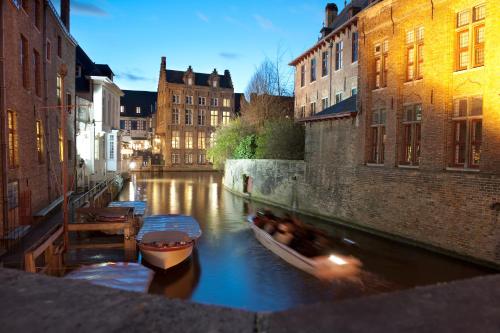 a couple of boats in a canal between buildings at Hotel Bourgoensch Hof in Bruges