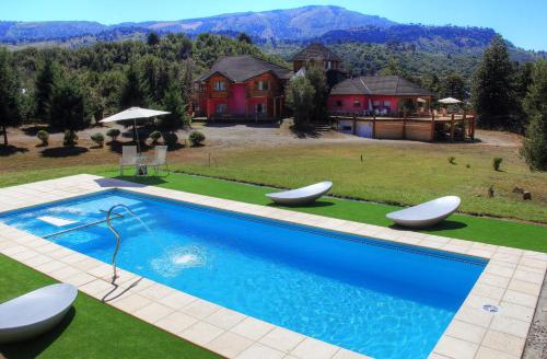 una casa con una gran piscina con 2 sillas blancas en Complejo Puerto Malén Club de Montaña en Villa Pehuenia