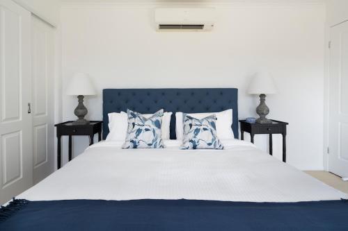 a bedroom with a large white bed with blue pillows at Villa Siena in Pokolbin