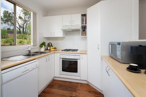 a white kitchen with a sink and a microwave at Villa Siena in Pokolbin