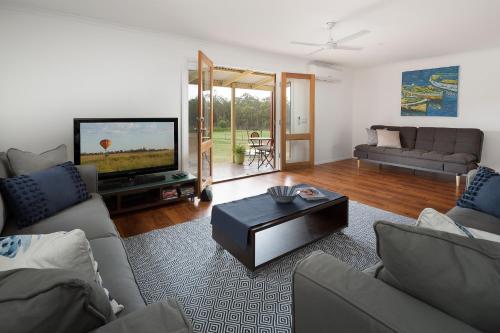 a living room with a couch and a tv at Villa Siena in Pokolbin
