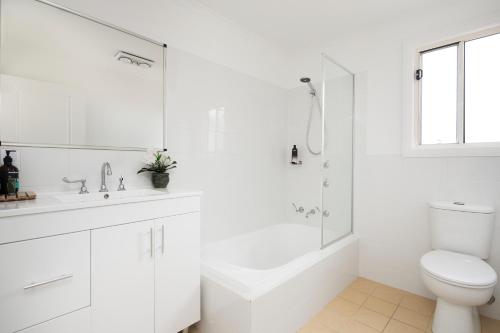 a white bathroom with a shower and a toilet at Villa Siena in Pokolbin