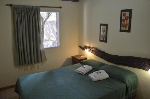 a bedroom with a bed with two pillows on it at Complejo de Cabañas Pach - Flo in San Marcos Sierras