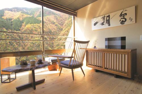a room with a table and a chair and a large window at Iya Onsen in Miyoshi