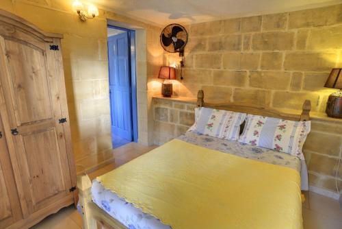 a bedroom with a yellow bed and a stone wall at Ta' Bertu Host Family Bed & Breakfast in Ħal Far