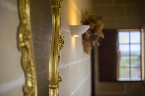 a gold mirror on a wall next to a window at Ta' Bertu Host Family Bed & Breakfast in Ħal Far