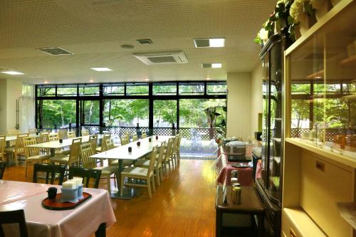 a dining room with tables and chairs and windows at Asia Hotel FUJISAN in Yamanakako