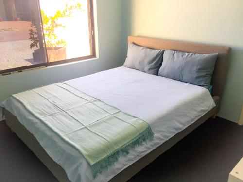 Una cama con sábanas blancas y una ventana en una habitación en Caversham B&B en Perth