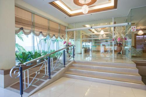 a lobby of a building with stairs and plants at Asia Cha-am Hotel in Cha Am