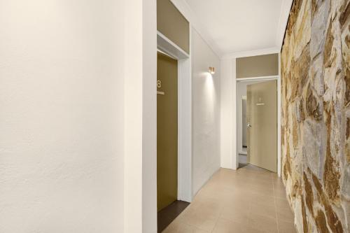 a hallway with white walls and a stone wall at Adelaide Road Motor Lodge in Murray Bridge