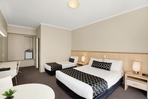 a hotel room with two beds and a desk at Adelaide Road Motor Lodge in Murray Bridge
