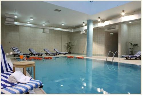 a large swimming pool with chairs in a hotel room at L'Arabia Hotel Apartments in Abu Dhabi