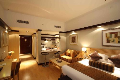 Habitación de hotel con cama y sala de estar. en L'Arabia Hotel Apartments, en Abu Dabi