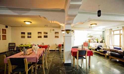 restauracja ze stołami i krzesłami w pokoju w obiekcie Oriental Hotel w mieście Leh
