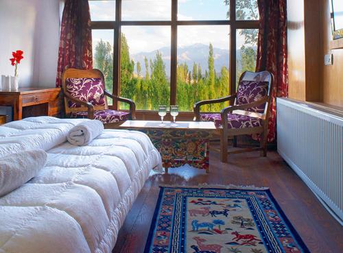 a living room with two chairs and a large window at Oriental Hotel in Leh