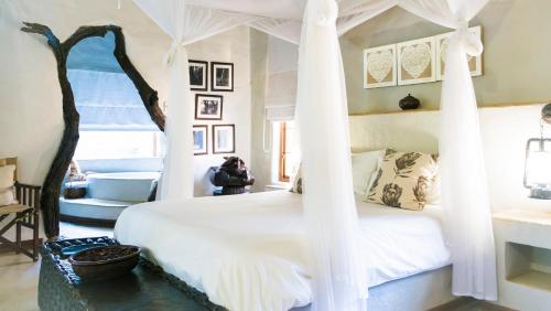 a bedroom with a white bed with a canopy at Moholoholo Ya Mati in Kampersrus AH