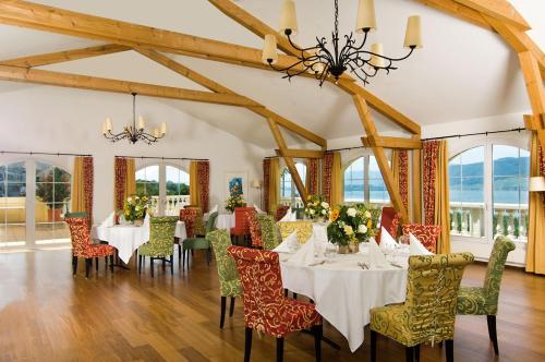 una sala da pranzo con tavoli, sedie e lampadario a braccio di Restaurant-Hotel Seeblick a Mörigen