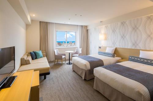 a hotel room with two beds and a table at Art Hotel Ishigakijima in Ishigaki Island