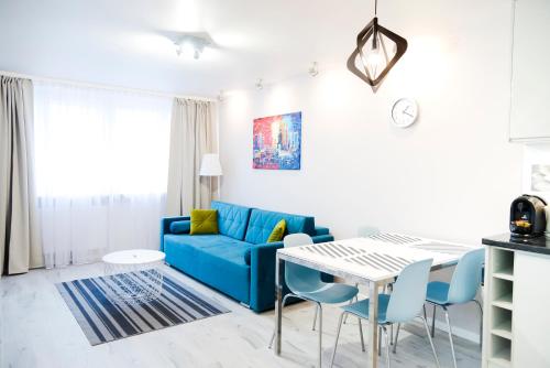 a living room with a blue couch and a table at Hosapartments City Center in Warsaw