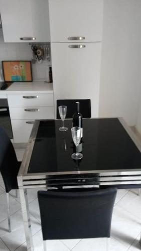 a black table with two glasses and a bottle of wine at Apartman Mirna in Premantura