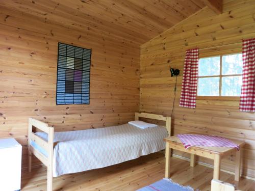 a log cabin bedroom with a bed and a table at Vanha-Pälsilä lakeside farm in Kuhmoinen