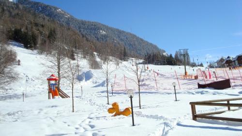 a snow covered playground with a toy animal in the snow at Hotel Biancaneve in Cogolo