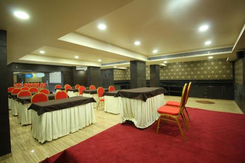 a conference room with tables and chairs and a red rug at Central Beacon Hotel in Surat