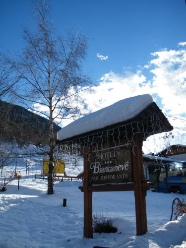 a sign with snow on top of it in the snow at Hotel Biancaneve in Cogolo