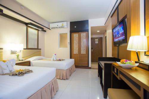 a hotel room with two beds and a television at Asia Cha-am Hotel in Cha Am