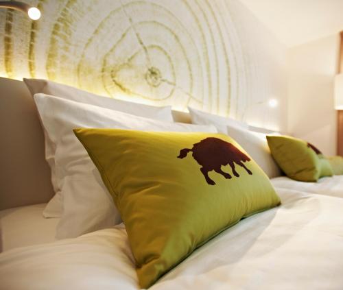 a bed with a green pillow with a bear on it at Steigenberger Airport Hotel Frankfurt in Frankfurt/Main