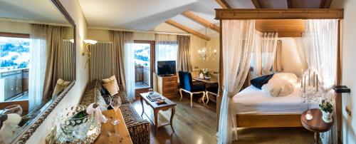 a bedroom with a canopy bed with a desk and a room with at Hotel Rosa Eco Alpine Spa Resort in Alpe di Siusi