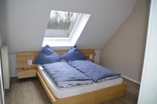 a bed with blue pillows in a room with a window at Ferienwohnung Tiberquelle in Dülmen