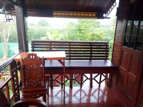 a table and chairs on a porch with a window at Ruenthip Homestay in Bangkok