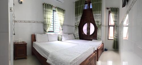 two beds in a room with two windows at Nhà nghỉ Sunrise in Quy Nhon