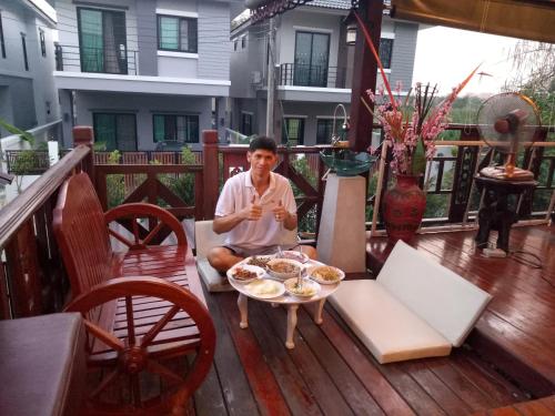 a man sitting on a deck eating food at Ruenthip Homestay in Bangkok