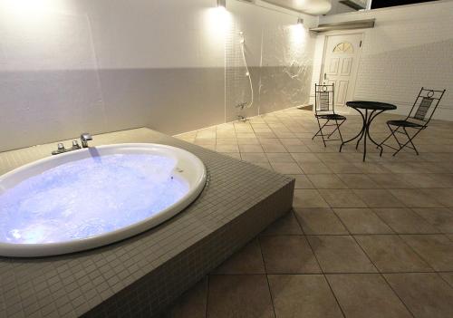 a bathroom with a tub with chairs and a table at Hotel neobibi (Adult Only) in Himeji