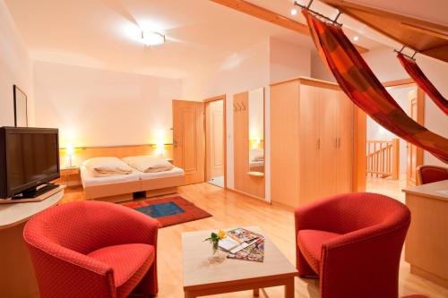 a living room with two red chairs and a television at Weingut und Gästehaus Berger in Gedersdorf