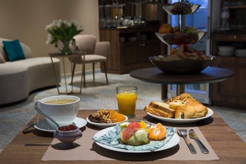 a table with plates of breakfast foods and a cup of coffee at Hôtel Mercure Paris Suresnes Longchamp in Suresnes