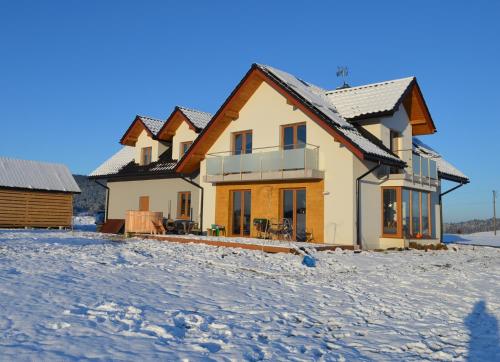 a house in the snow in front at Pokoje na Wzgórzu in Kasina Wielka