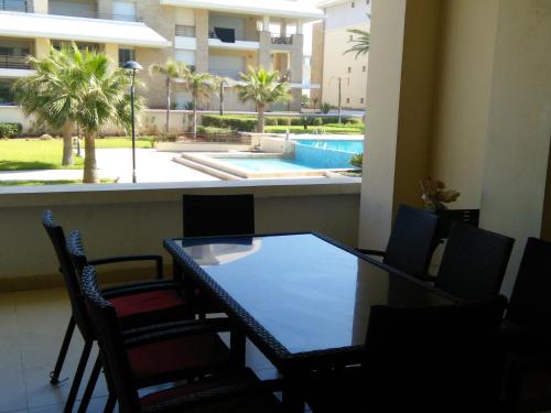 a table and chairs in a room with a swimming pool at Prestigia PDN in Sidi Bouqnadel