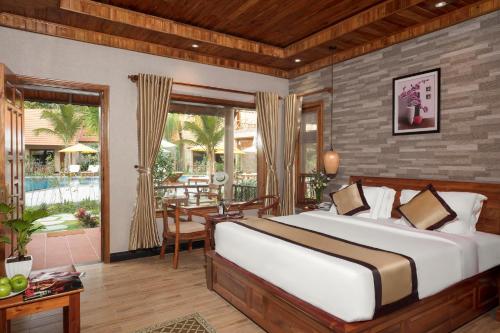a bedroom with a bed and a table and a patio at Golden Topaz Phu Quoc Resort in Phu Quoc