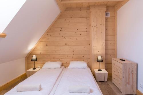 a bed in a room with a wooden wall at Domek Przystań Górska in Zakopane