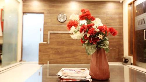 un vaso pieno di fiori rossi e bianchi su un tavolo di Pals Inn a Nuova Delhi