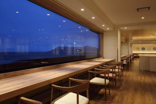a bar with a row of chairs and a large window at Heiseikan Shiosaitei Hanatsuki in Hakodate