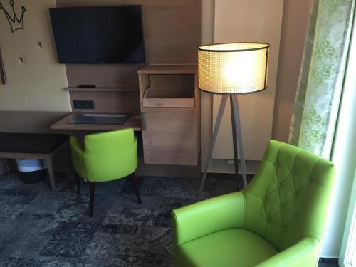 a living room with a green chair and a desk at Landhotel Witte-König in Garrel