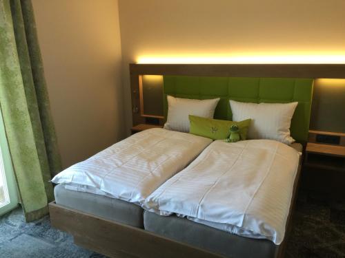 a bedroom with a large bed with a green headboard at Landhotel Witte-König in Garrel