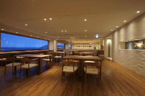 a restaurant with tables and chairs and a large window at Heiseikan Shiosaitei Hanatsuki in Hakodate