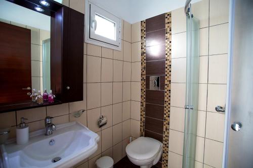 ein Bad mit einem Waschbecken, einem WC und einer Dusche in der Unterkunft GoldenHill Studios&apartments in Skiathos-Stadt