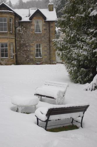 two benches covered in snow in front of a house at Lubnaig Guest House in Callander