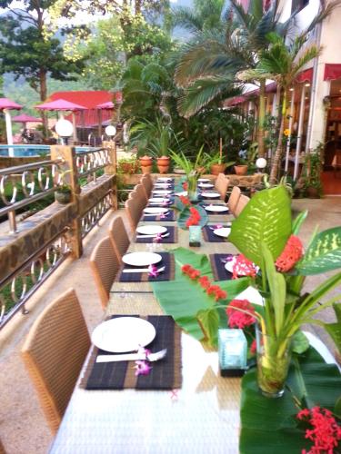 una lunga fila di tavoli con piatti bianchi e piante di Top Resort a Ko Chang
